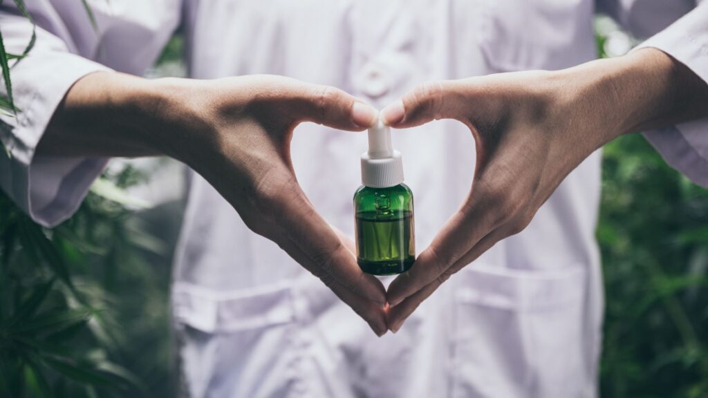 person holding a CBD bottle with their hands shaped like a heart